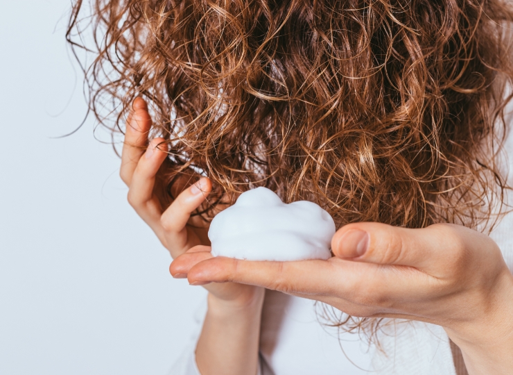 Vrouw die de Curly Girl Methode toepast, met nadruk op het verzorgen en definiëren van haar natuurlijke krullen na een behandeling bij Salon Warrig in Sint Pancras.