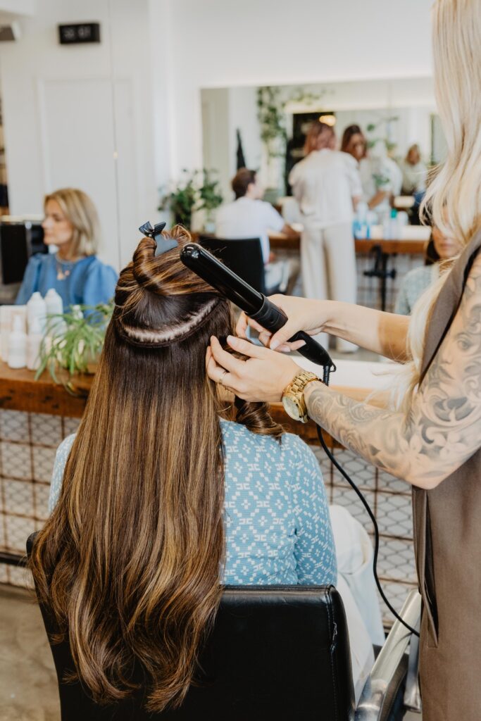 Vrouw laat hairextensions plaatsen door stylist in Salon Warrig in Sint Pancras.