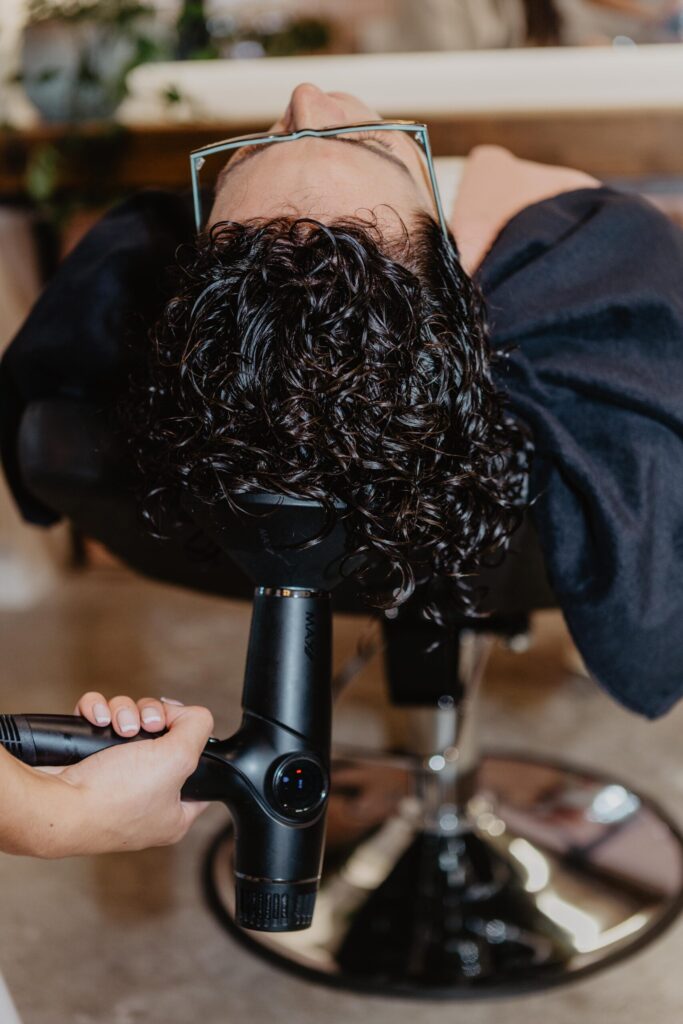 Foto van vrouw met krullen die wordt gestyled door een gecertificeerde krullenkapper van Salon Warrig in Sint Pancras.